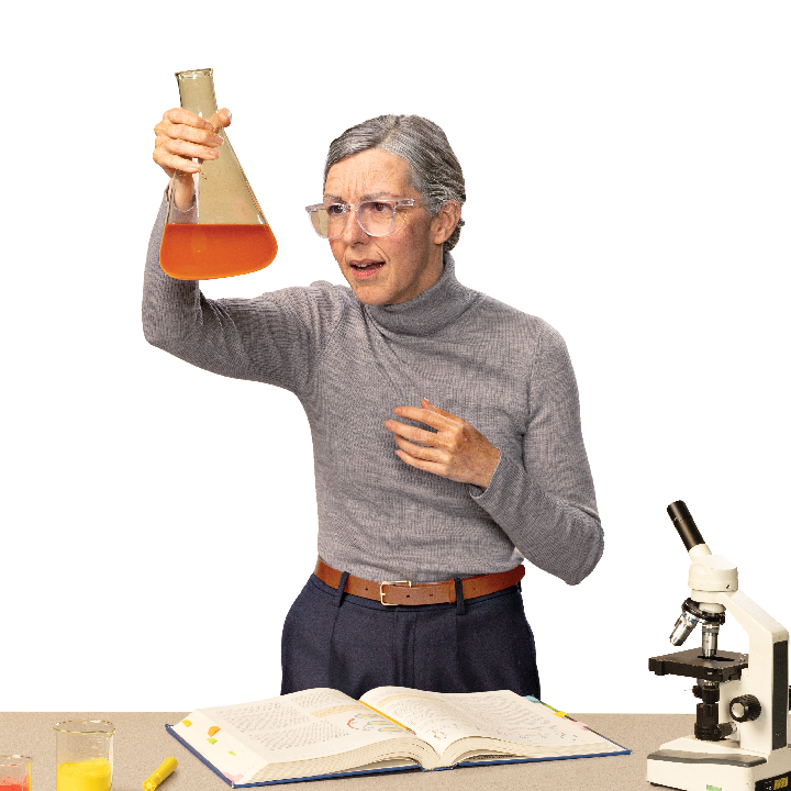 older female science teacher holding up a beaker in class